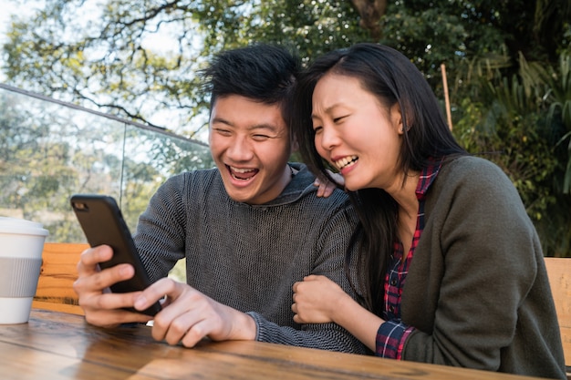 Asiatisches Paar, das das Handy betrachtet.