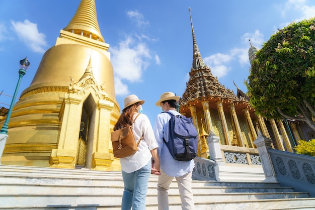 Asiatisches Paar freut sich, dass Touristen in ihren Ferien im Tempel Wat Phra Kaew in Bangkok, Thailand, mit Maske reisen, um sich vor Covid-19 zu schützen