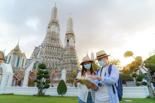 Asiatisches Paar glückliche Touristen, die in den Ferien reisen und im Wat Arun Tempel in Bangkok, Thailand, halten