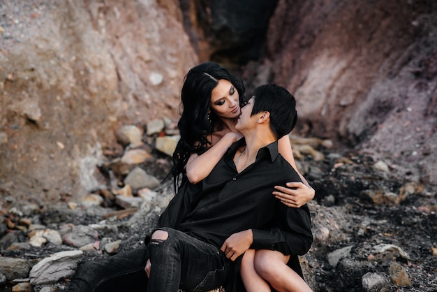Asiatisches Paar in den Umarmungen, die auf den Felsen sitzen. Liebesgeschichte