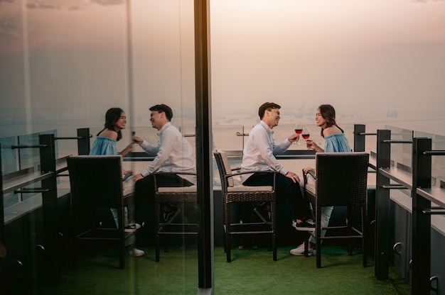 Asiatisches Paar jubelt Wein mit romantischer Aussicht auf den Tisch im Restaurant HotelUrlaubDinner