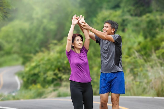 Asiatisches Paar mittleren Alters, das Muskeln vor dem Joggen im Park dehnt