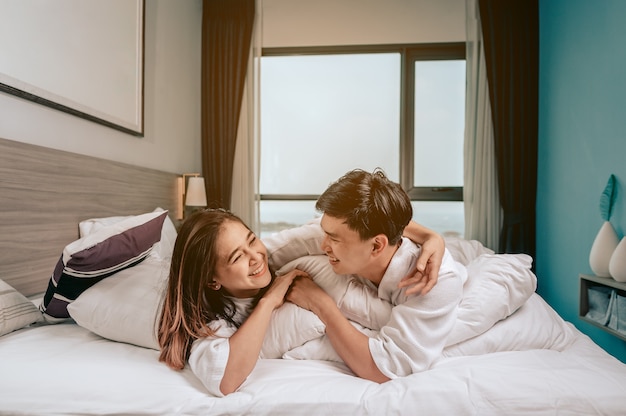 Asiatisches Paar spielt und entspannt sich auf dem Bett im Schlafzimmer im modernen ZuhausePaar am Valentinstag