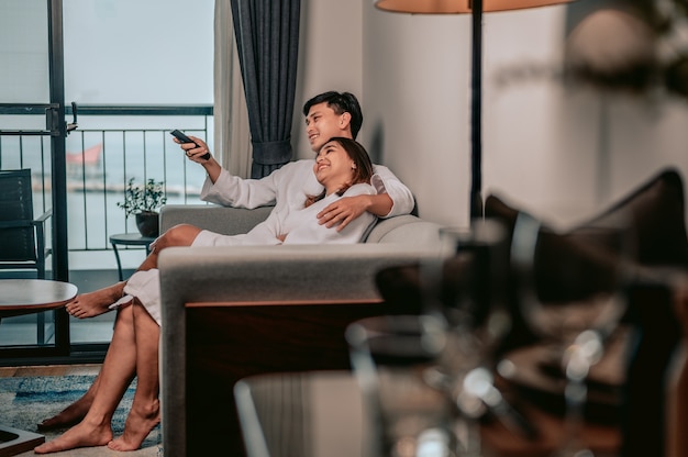 Asiatisches Paar vor dem Fernseher sitzt auf einem Sofa im Wohnzimmer zu Hause