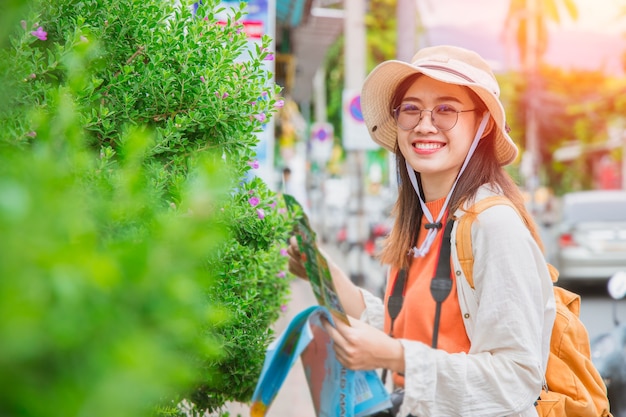 Asiatisches Reisendesmädchen jugendlich oder Tourist glückliches Lächeln reisen in den Sommerferien mit Kartenspaziergang auf der Straße