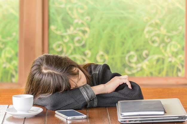 Asiatisches schlafendes Mädchen beim Sitzen am Schreibtisch