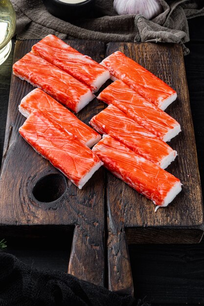 Asiatisches Snack-Surimi-Set, auf Holzschneidebrett, auf schwarzem Holztischhintergrund