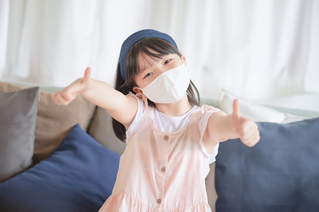 Asiatisches süßes Mädchen mit hygienischer Gesichtsmaske zur Vorbeugung von Coronavirus oder Covid19