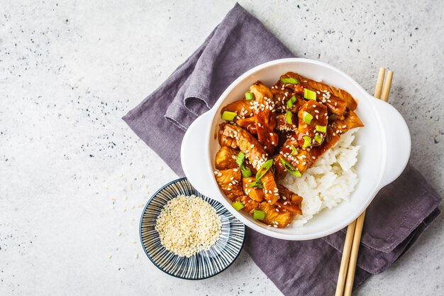 Asiatisches teriyaki Huhn mit Reis, indischem Sesam und Frühlingszwiebeln in der weißen Schüssel.