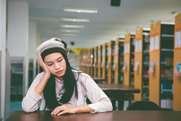 Asiatisches trauriges Mädchen im Vintage-Stil der Bibliothek