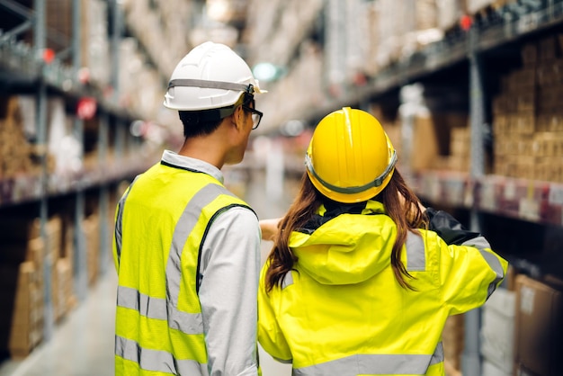 Asiatisches Zwei-Ingenieur-Team-Versandauftragsdetail auf Tablet-Check-Waren und -Vorräten in Regalen mit Warenhintergrundinventar in der Fabriklagerlogistikindustrie und im Geschäftsexport