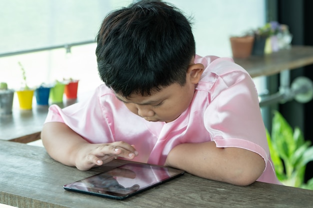 Asiatsjunge, der mit digitaler Tablette spielt