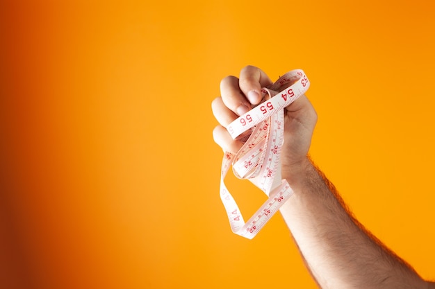 Asideros de cinta métrica sobre fondo naranja