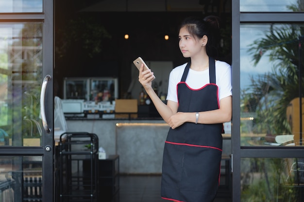 Asien-frau, die in der freizeit handy in der kaffeestube mit einsamem verwendet.