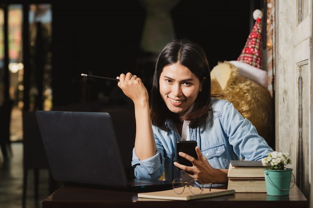 Asien-Frau, die Smartphone, Personal Computer arbeitet mit glücklichem verwendet.