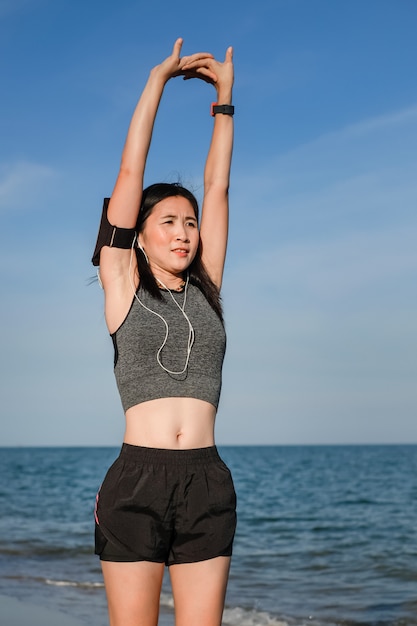 Asien-Frau im Sport trainieren und laufen auf dem Strand.