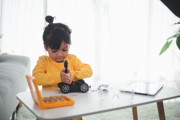 Asien-Studenten lernen zu Hause die Codierung von Roboterautos und Elektronikplatinenkabeln in STEM, STEAM, Mathematik, Ingenieurwissenschaften, Technologie, Computercode im Robotik-Konzept für Kinder.