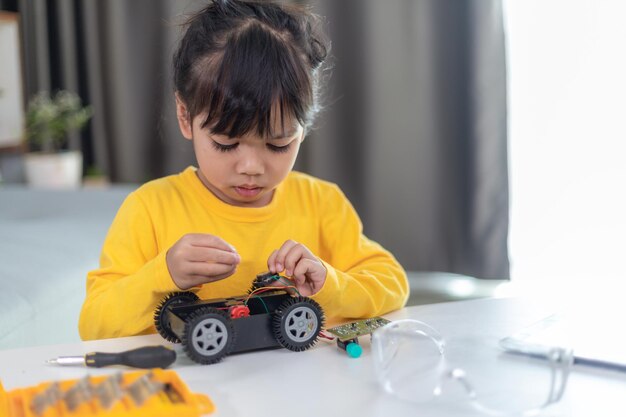 Asien-Studenten lernen zu Hause die Codierung von Roboterautos und Elektronikplatinenkabeln in STEM, STEAM, Mathematik, Ingenieurwissenschaften, Technologie, Computercode im Robotik-Konzept für Kinder.