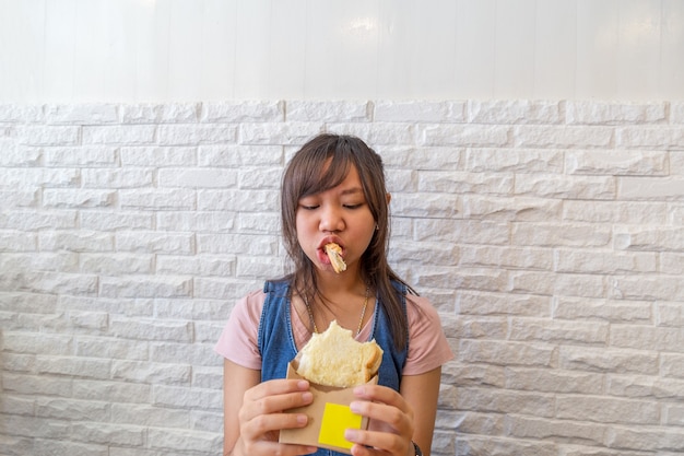 Asien-Teenager-Mädchen, das Käsebrotgrill im Restaurant oder im Café isst