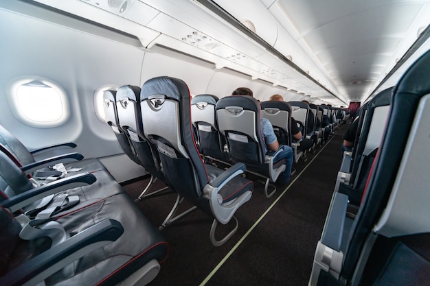 Asientos de cabina de avión con pasajeros. Clase económica de las nuevas aerolíneas de bajo costo más baratas. Viaje de viaje a otro país. Turbulencia en vuelo.