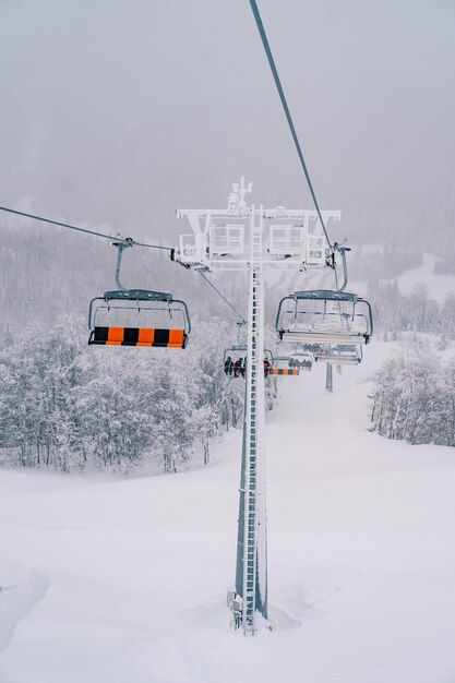 Foto los asientos de elevación de cuatro personas se mueven a lo largo de un cable por una ladera cubierta de nieve