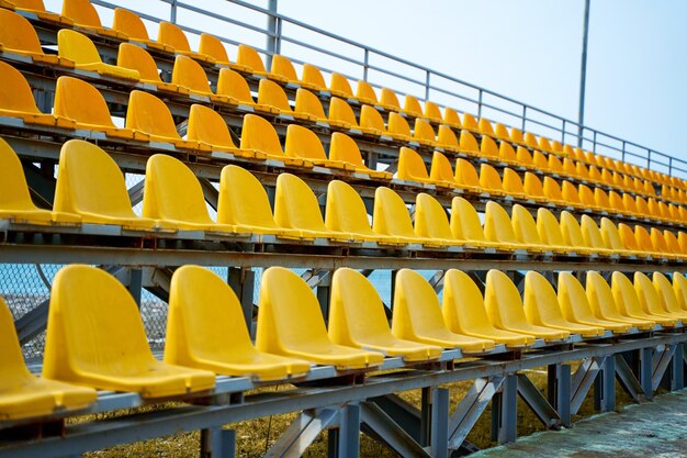 Asientos de plástico amarillo en el podio de un pequeño campo deportivo