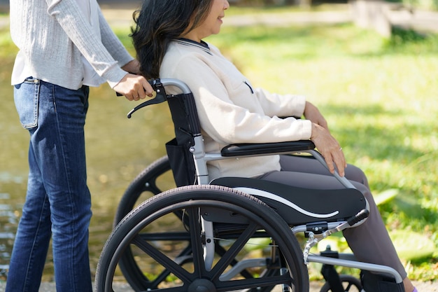 Asilo de ancianos Joven cuidadora ayudando a una anciana en silla de ruedas