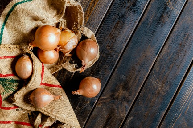 Asimiento de la mano bolsa de tela de cebolla fresca aislada en la superficie de madera b