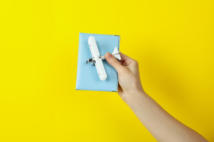 Foto asimiento de la mano femenina avión de juguete y pasaporte sobre fondo amarillo