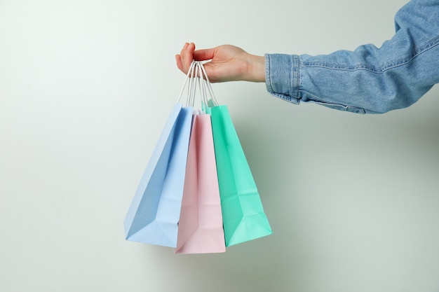 Asimiento de la mano femenina bolsas de papel sobre fondo blanco.