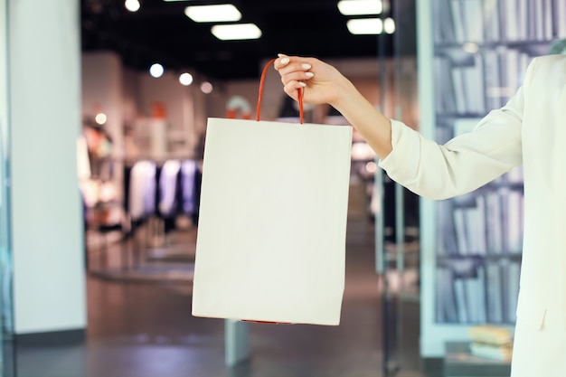 Asimiento de la mano de la mujer bolsa de compras en la tienda de ropa.