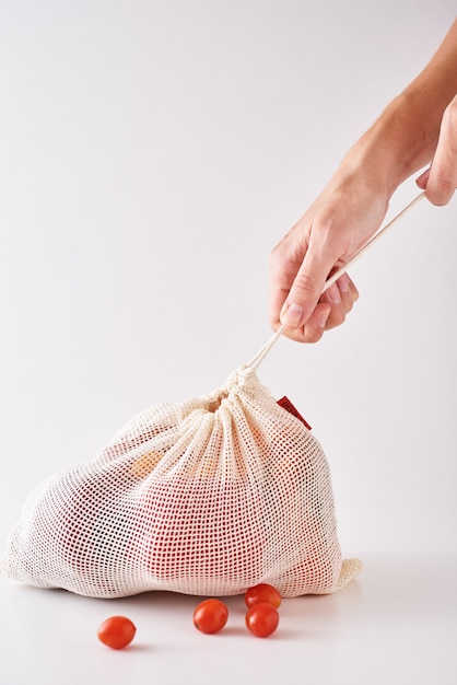 Asimiento de la mano de mujer verduras orgánicas frescas en bolsa textil.