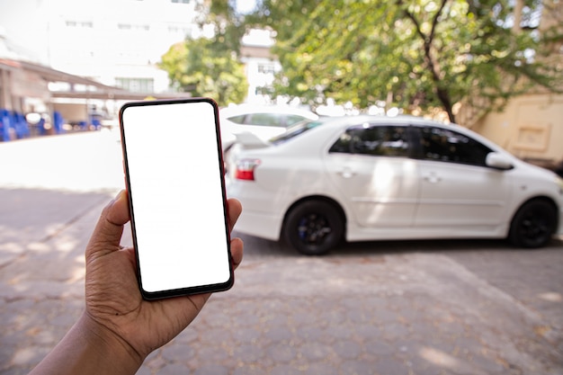 asimiento de la mano pantalla en blanco en el móvil, teléfono celular, tableta en coche blanco borrosa.