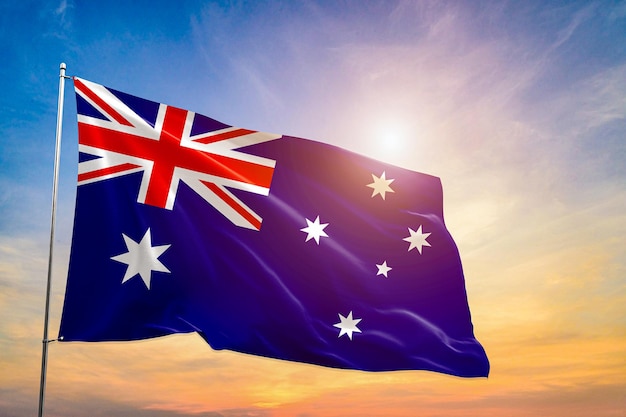 Asimiento nacional de la bandera de Australia bajo el cielo azul en la playa con la luz del sol