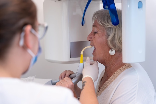 Asistente dental de clínica dental con una anciana en la sala de rayos x explicando cómo tienen que poner la voz