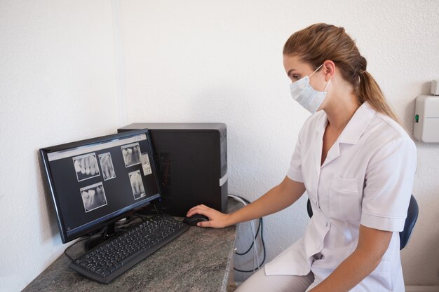 Foto asistente dental mirando radiografías en la computadora