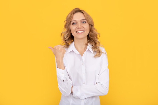 Asistente ejecutiva o empleada empresaria jefa directora ejecutiva señalando con el dedo en el espacio de la copia alegre mujer rubia con camisa blanca oficinista de negocios estilo casual chica de cuello blanco