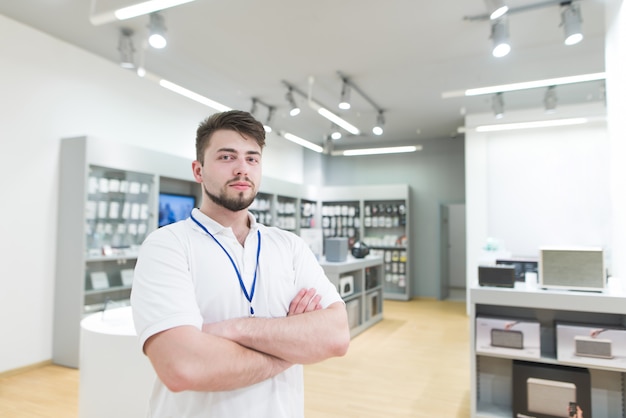 Asistente guapo está parado en la superficie de una tienda de tecnología