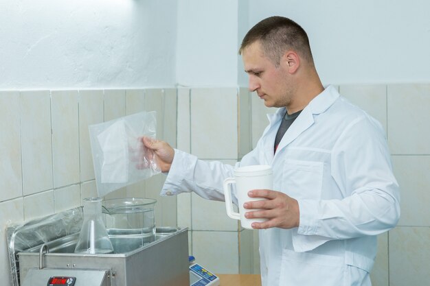 Asistente de laboratorio con bata blanca hace pruebas en la oficina