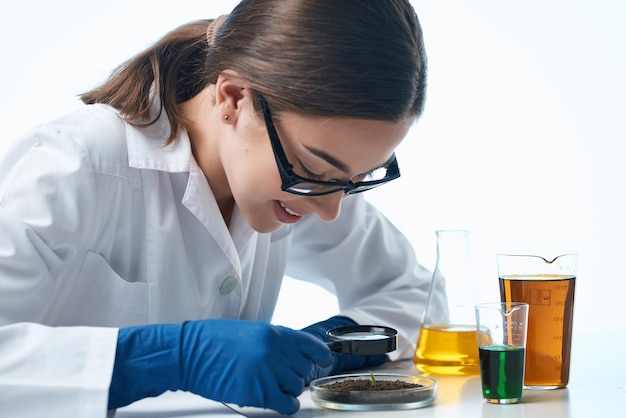 Asistente de laboratorio femenino mirando a través de una solución química de seguimiento de biología de lupa