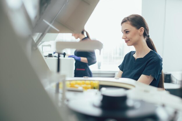 Asistente de laboratorio joven alegre sonriendo y trabajando con equipo de laboratorio