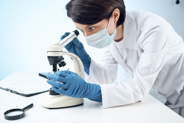 asistente de laboratorio con una máscara médica mirando a través de un microscopio experimento de investigación profesional foto de alta calidad