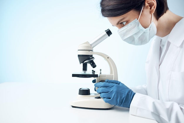 Asistente de laboratorio mujer máscara médica microscopio diagnóstico biotecnología foto de alta calidad