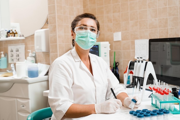 Asistente de laboratorio tiene tubos de ensayo para análisis citológico y ginecológico Mujer científica que trabaja en laboratorio médico