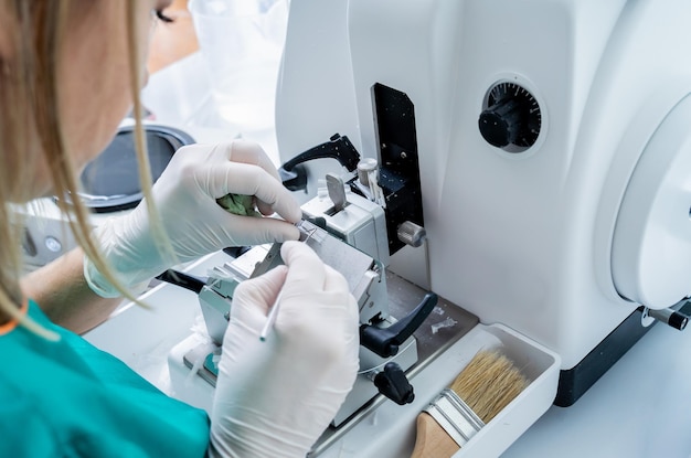 El asistente de laboratorio trabaja en una sección de microtomo rotatorio y en la fabricación de portaobjetos de microscopio