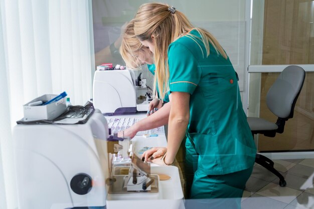 El asistente de laboratorio trabaja en una sección de microtomo rotatorio y en la fabricación de portaobjetos de microscopio