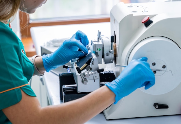 Asistente de laboratorio trabaja en una sección de micrótomo rotatorio y hace portaobjetos de microscopio