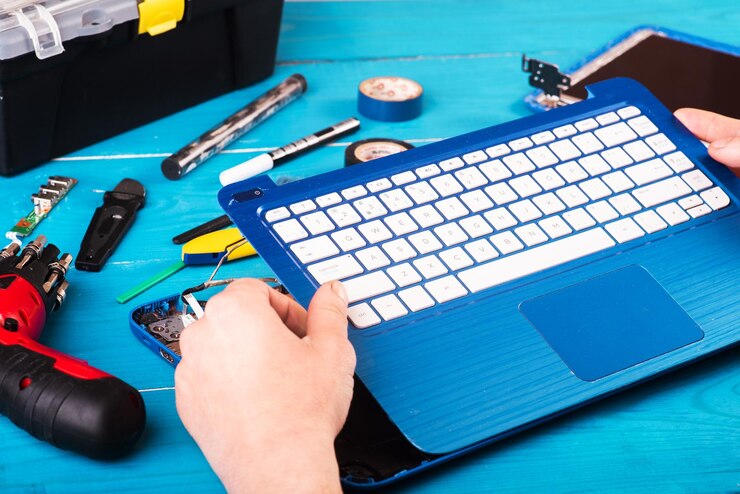 Foto el asistente repara la computadora portátil con herramientas y manos en la vista superior de la mesa de madera azul