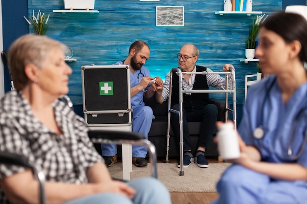 Asistente social discutiendo la medicación sanitaria con ancianos pensionista discapacitado