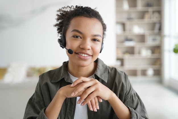 Asistente virtual La joven afro con auriculares es operadora del servicio de atención al cliente desde casa